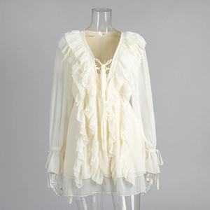 Detailed close-up of cream chiffon dress with layered ruffles and lace-up V-neckline