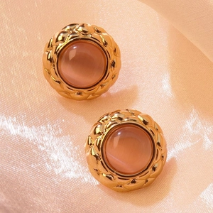 Close-up of vintage gold-rimmed quilted earrings with pink opal stones on silk