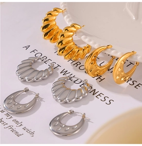 Detailed close-up of textured gold and silver U-shaped earrings on a ceramic display