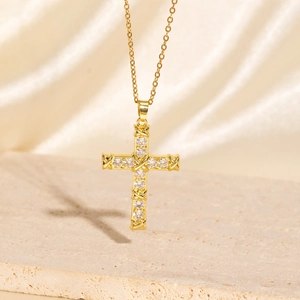 Close-up of golden cross necklace with zircons and X-shaped wrap on silk background