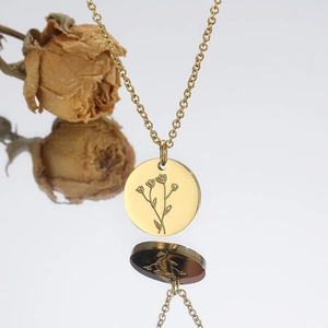 Gros plan d'un collier avec pendentif fleur de naissance en acier doré sur reflet