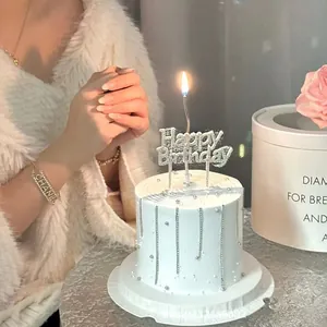 Detail of elegant white birthday cake with silver pearls and a golden Happy Birthday topper