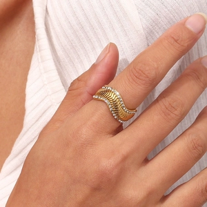 Macro shot of gold-plated wavy ring with sparkling cubic zirconia on a model's hand