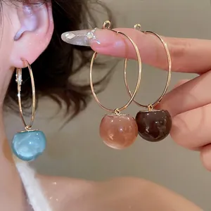 Hoop earrings with resin sphere charms in blue, pink and brown on golden metal rings