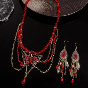 Parure luxe avec collier papillon en cristal rouge et boucles d'oreilles sur miroir noir