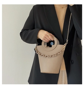 Close-up of khaki PU leather bucket bag featuring round handle and chunky chain detail