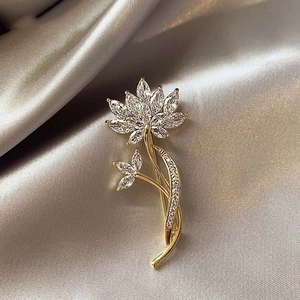 Macro shot of gold-plated flower brooch with marquise-cut crystals on silk background