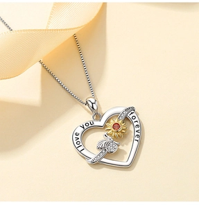 Macro detail of S925 silver heart necklace with bee, sunflower, and I love you forever engraving