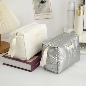 Detail of quilted bow texture on silver and cream makeup bags with ribbon zippers