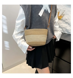Detail view of khaki woven crossbody bag with white stripes and adjustable strap