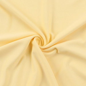 Close-up of the light yellow knitted fabric texture with spiral pleats and soft grain