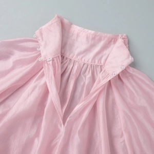 Detail of pink satin high collar with delicate pleats and button closure at back