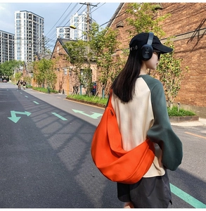 Detail of orange crescent oxford shoulder bag with smooth texture in outdoor setting