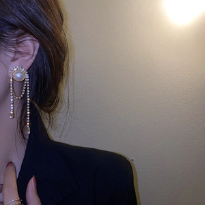 Close-up of sparkling rhinestone tassel earrings worn by a model in a retro style