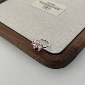Macro shot of silver butterfly ring with pink stones on a walnut wooden tray
