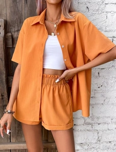 Detail of orange casual two-piece set featuring short-sleeve shirt and elastic waist shorts