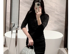 Mirror selfie showing the silver sequined shell evening clutch paired with a black dress