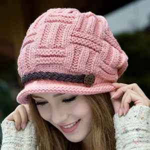 Close-up of pink knit hat featuring woven leather strap and vintage metal button detail