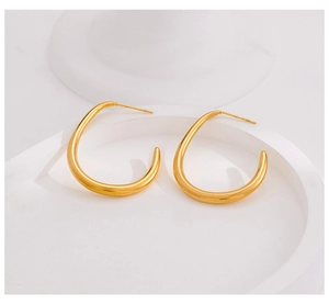 Vue macro de boucles d'oreilles goutte dorées avec finition polie sur socle blanc