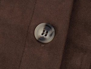 Macro detail of dark brown suede jacket texture and marble patterned resin button