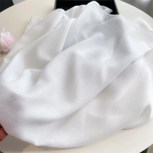 Detailed macro shot of white linen cotton scarf showing delicate woven texture and fabric shine