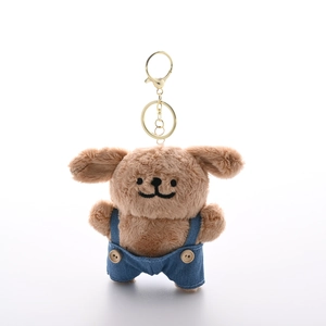 Cute brown plush dog keychain in blue denim overalls on a white background