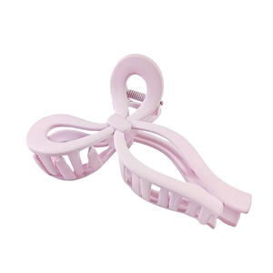 Macro view of matte pink bow hair claw clip showing smooth texture and metal spring