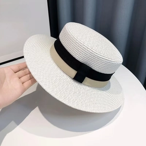 Detail showing the fine texture of a white straw boater hat with a chic two-tone ribbon