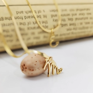 Macro detail of gold stainless steel snake chain with elegant initial m letter pendant