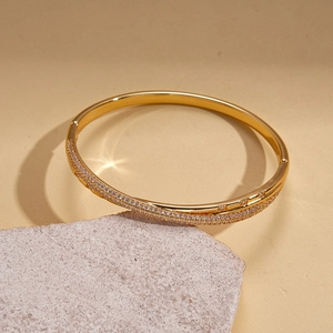 Detail of 18k gold plated hinged bangle with pavé-set zircons on a textured stone