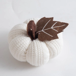 Close-up of a white knitted pumpkin harvest ornament with brown felt leaf and stem