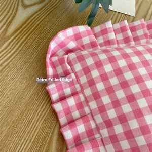 Detail of pink gingham fabric featuring retro ruffle edges and woven cotton texture