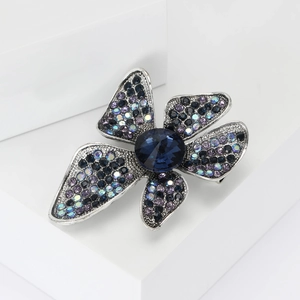 Vintage alloy flower brooch with blue crystal rhinestones on a white display stand
