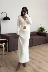 Dettaglio della trama in maglia a coste bianca di un cardigan con scollo a V e gonna lunga