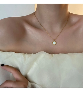 Detail of white mother of pearl pendant on elegant 18K gold plated chain necklace