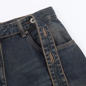 Detalle de vaqueros azul oscuro que muestra el botón metálico, costuras y tejido denim