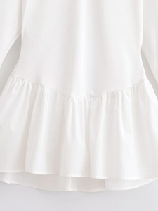 Close-up detail of white ruffled hem with pleated stitching on minimalist cotton dress