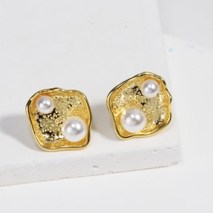 Detailed view of 18k gold plated irregular lava earrings with white pearl inlays