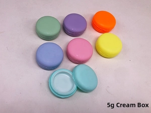 Detail view of seven colorful 5g macaron-shaped plastic cosmetic jars for cream and makeup