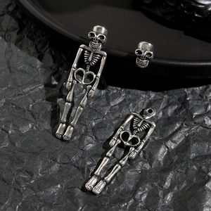 Detailed close-up of vintage silver skull earrings and skeleton pendant set with aged finish