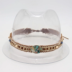 Detail of hand-woven ethnic hat band with turquoise stones and wooden beads on white