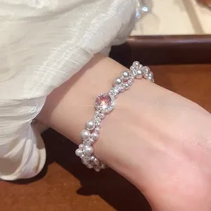 Three-layer pearl bracelet featuring pink zircon centerpiece on woman's wrist