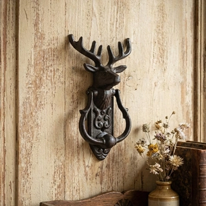 Vintage cast iron deer head door knocker in bronze finish mounted on rustic wood surface