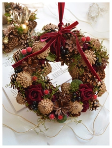 Close-up of Christmas wreath with pine cones, red roses, berries and velvet ribbon bow