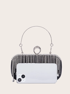 Mini black evening clutch with silver rhinestone tassels and ring handle beside a phone