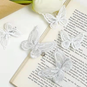 Detailed embroidery on white lace butterfly hair clips resting on vintage book pages