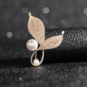 Macro detail of golden leaf brooch featuring small pearls and elegant drop pearl accents