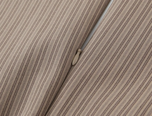 Detailed macro view of the invisible zipper on brown and beige striped fabric texture