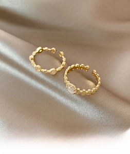 Close-up of vintage gold open rings with white opal stones on elegant silk fabric
