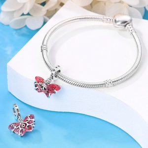 Close-up of silver beaded bracelet featuring a red butterfly charm and enamel detail